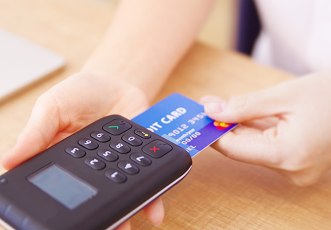 黒い決済端末にデビットカードを挿入して支払い手続きを行う様子