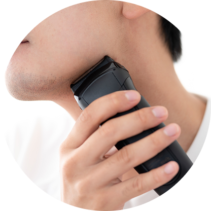 電動シェーバーでヒゲを剃る男性のあごのクローズアップ